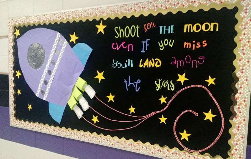 Bulletin board with a large paper space ship. Text reads Shoot for the moon. even if you miss you'll land among the stars. (Back-to-School Bulletin Boards)