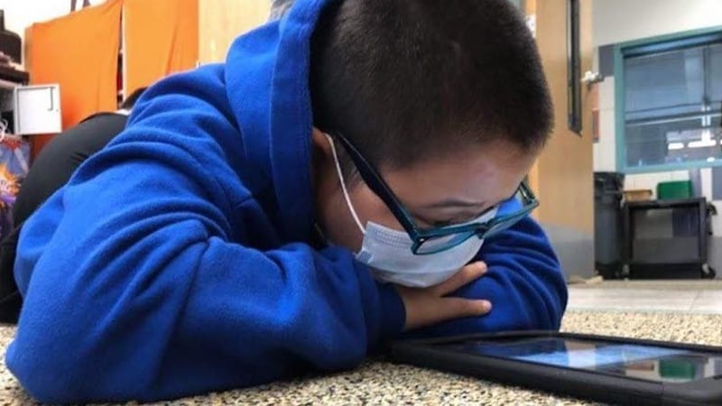 A student wearing a mask getting reading support from Bookshare.