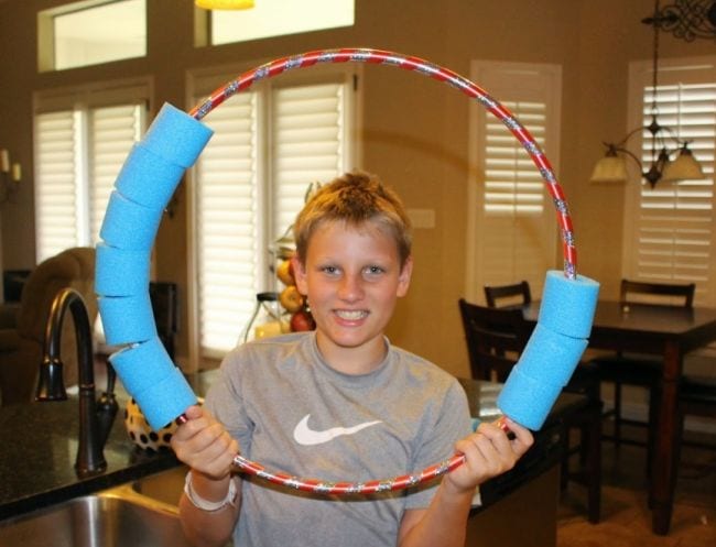 Student holding a hula hoop with cut up pool noodle pieces around the edges (Number Bonds Activities)