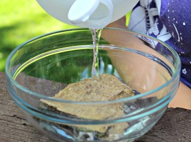 Child pouring vinegar over a rock in a bowl