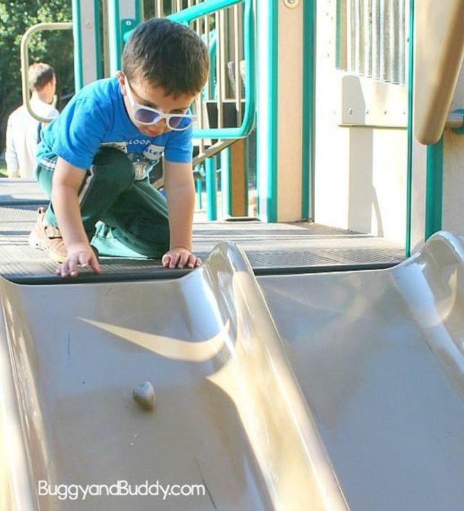 Child sending a rock down a playground slide