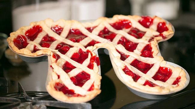 Moule à tarte en forme de symbole pi contenant une tarte rouge avec une croûte en treillis