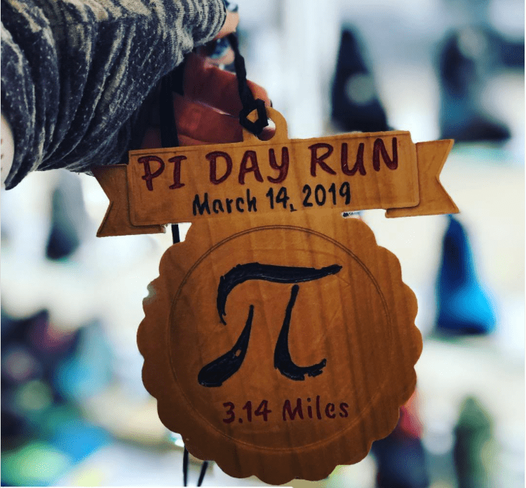 Houten plaquette met het pi-symbool, 3,14 mijl en de titel van de pi-dag loop