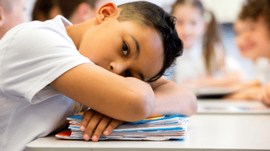 young hispanic boy with head down on his desk at school - Classroom Trauma Triggers