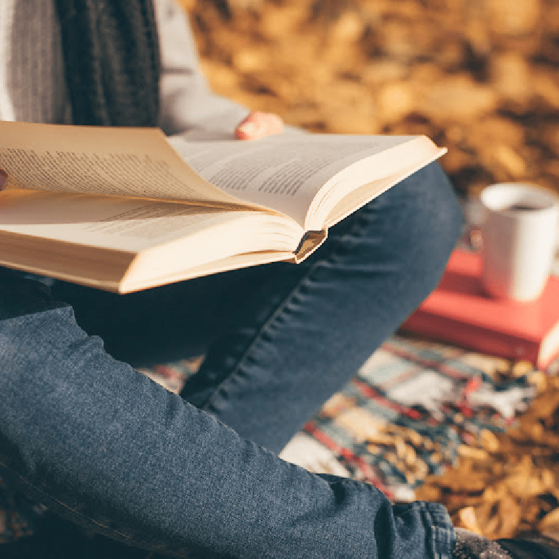 Reading outside in the fall with cup of coffee