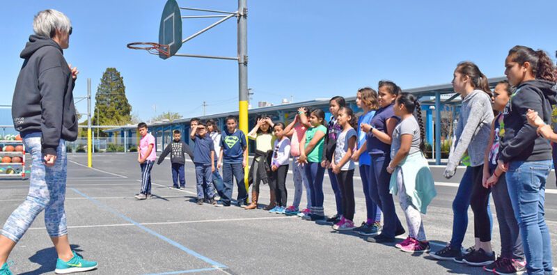 A teacher stands facing a long line of students as they prepare to play this old school recess game.