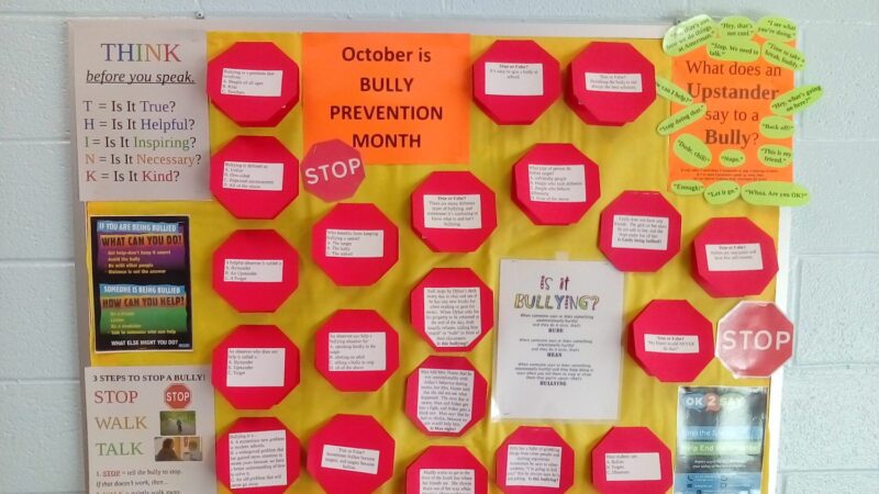 A bulletin board shows multiple stop signs that open with a flap. The outside has a question about bullying and the inside reveals the answer.