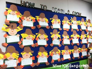 Many cute, cutout scarecrows adorn a bulletin board. Each one is holding a writing prompt. Text reads 