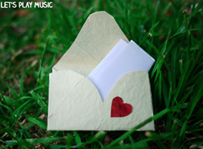 A white envelope with a red heart on it is open with a folded piece of white paper inside.