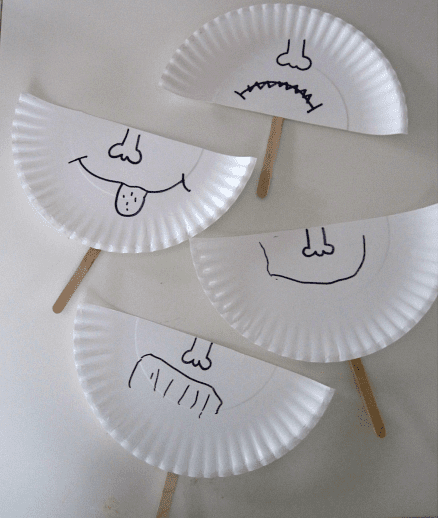 Masks made from paper plates and popsicle sticks with faces showing different emotions drawn on them, as an example of social-emotional activities