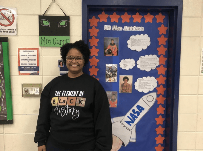 Woman smiling in front of door with drawing of NASA spaceship on it