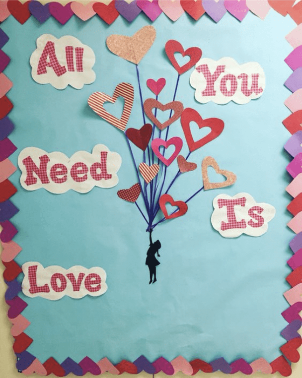 Board with cutout of balloons shaped like hearts and words All you need is love