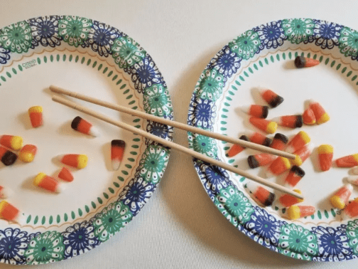 Plates with candy corn and chopsticks on them