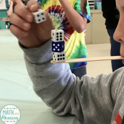 Kid balancing dice on a Popsicle stick, as an example of minute to win it games for kids