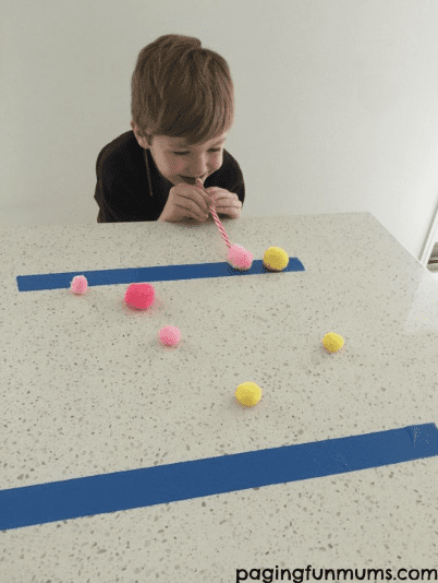 Kid blowing fuzz balls with a straw