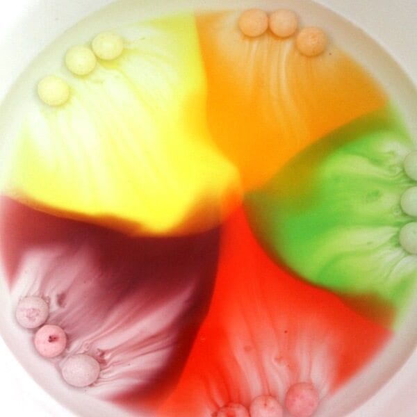 A bowl with melted Skittles inside creating a rainbow effect