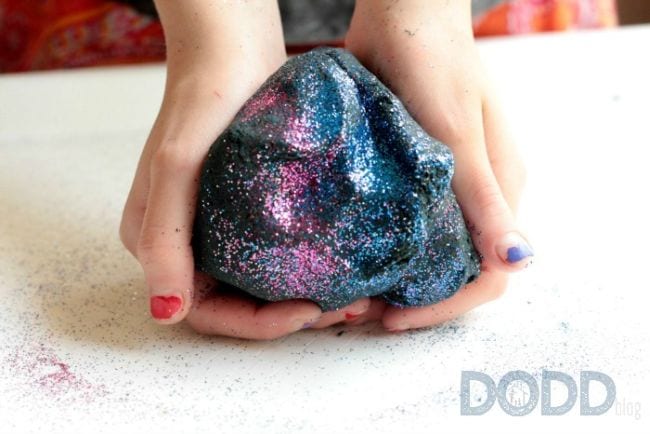 space activities for kids- two hands holding gray play dough flecked with pink and blue glitter