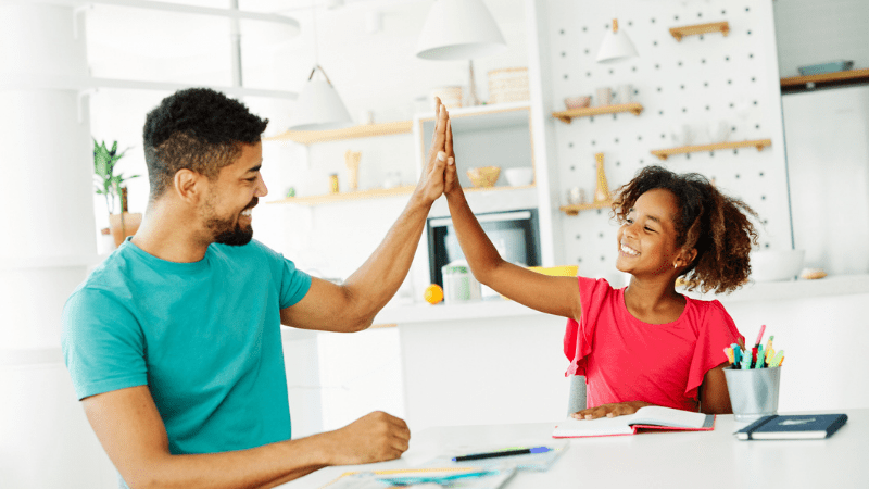 Father high-fiving daughter at the kitchen table