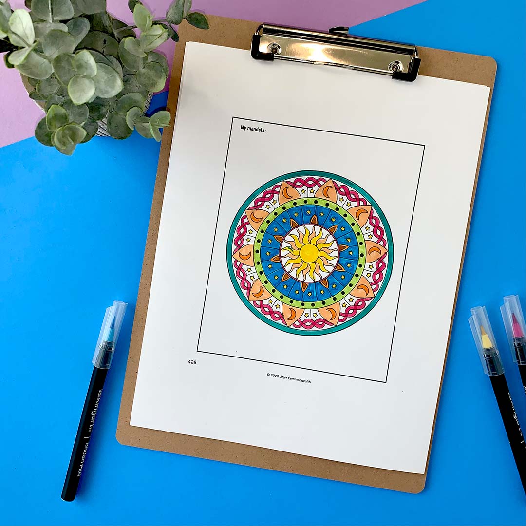 Photograph of a hand-colored mandala on paper on a bright blue background