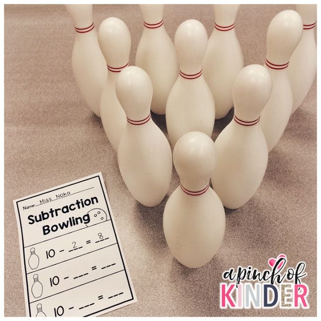 plastic bowling pins in formation with a subtraction bowling worksheet in front of them