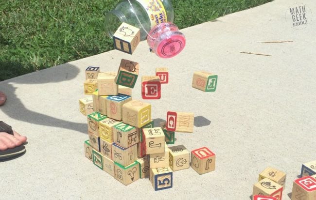 a stack of wooden blocks being knocked over by a pink plastic yoyo