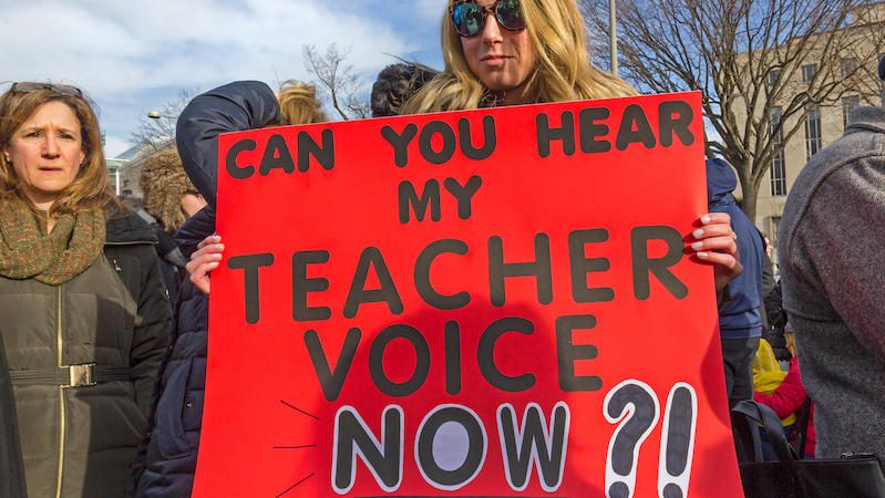 Teacher holding protest sign - example of teacher shortage