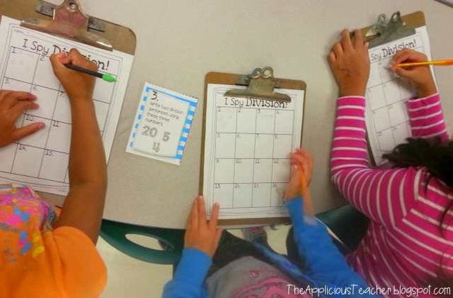 Students using pencils to write on I Spy Division worksheets on clipboards (Teaching Division)