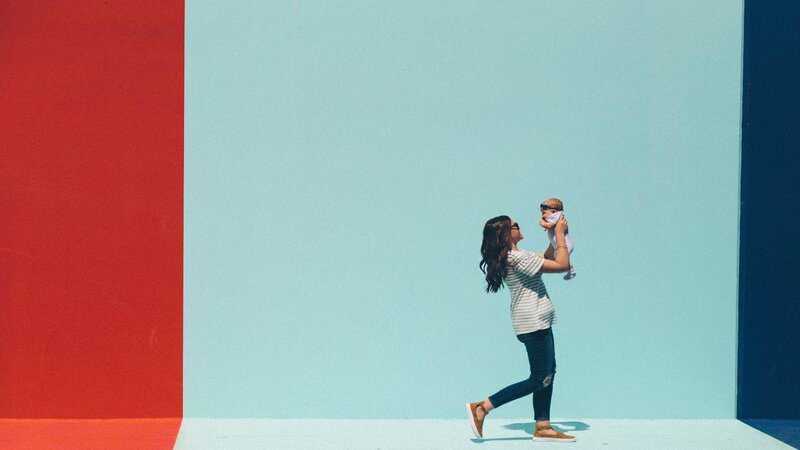 A teacher and mother plays with child between colorful painted boundaries