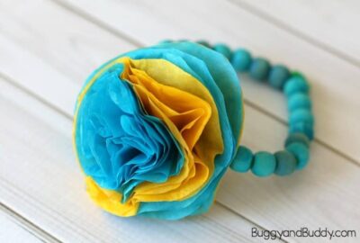 A blue and yellow bracelet made from tissue paper and wooden beads, as an example of summer crafts for kids
