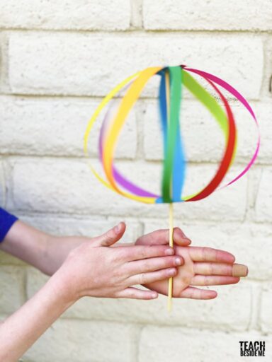 a whirligig made from colorful paper strips and a stick, as an example of summer crafts for kids