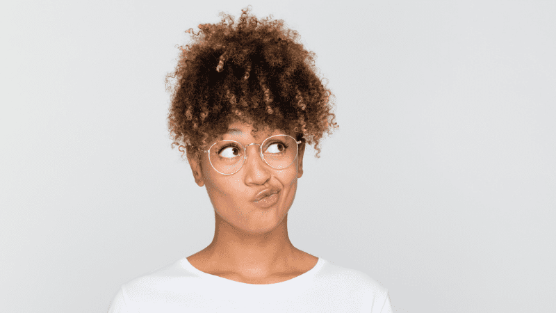 Black woman in white shirt making a bored expression in front of a white background