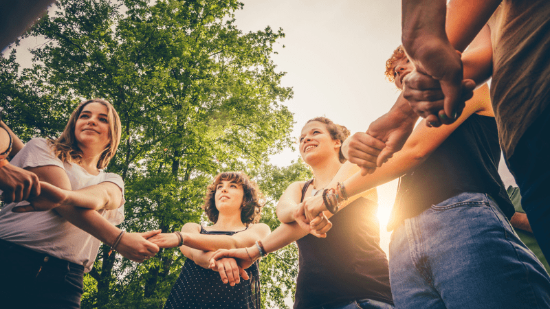 Teens playing Simon Says in a circle with crossed arms and holding hands