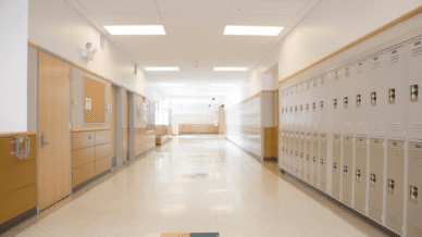View of a school hallway with lockers on the right side of the hall and doors into classrooms/offices on the left