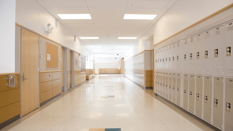 View of a school hallway with lockers on the right side of the hall and doors into classrooms/offices on the left