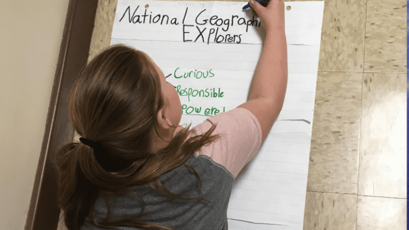 student writes explorer characteristics on poster