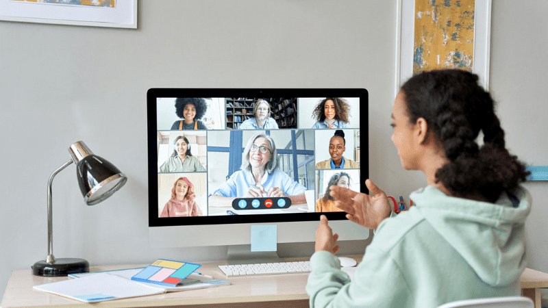 Female teen sitting in front of a computer attending a virtual class led by a virtual teacher