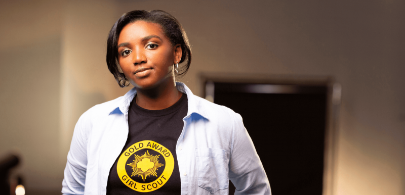 Girl scout standing in classroom wearing a Gold Award Girl Scout shirt
