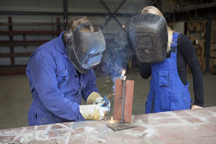 two people in masks and aprons welding