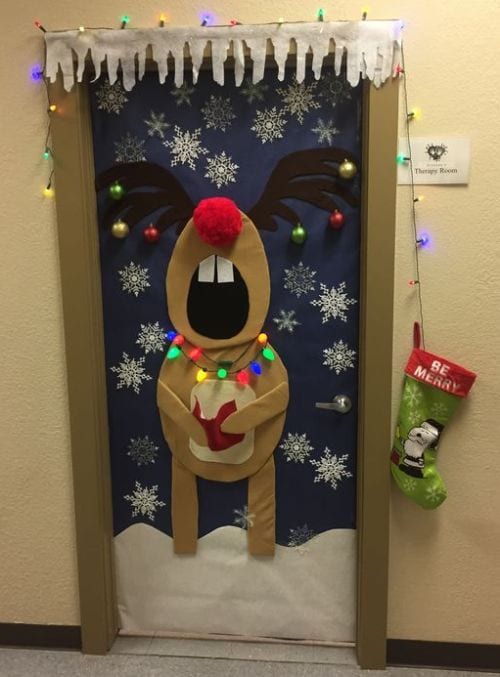 Classroom door decorated with a silly singing reindeer surrounded by snowflakes