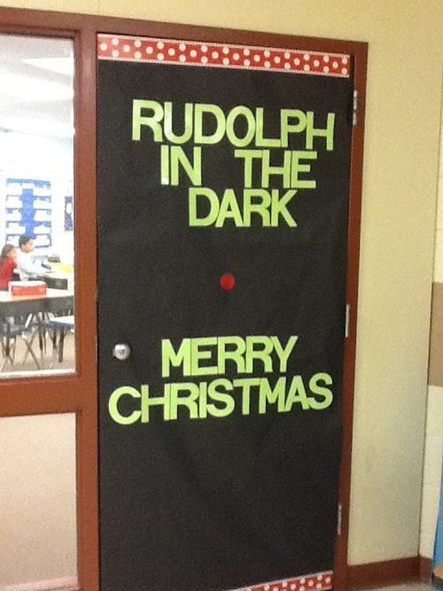 Classroom door covered in black paper with a red dot in the middle. Text reads "Rudolph in the dark." (Winter Classroom Doors)