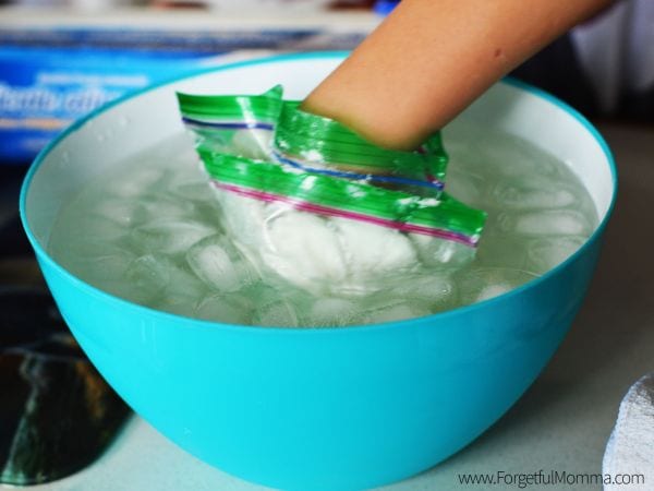 Child holding their hand wrapped in a plastic bag in a bowl of ice and water