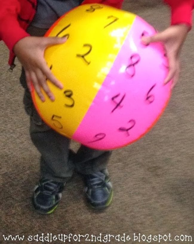 Student holding a beach ball marked with numbers (Math Facts Practice)