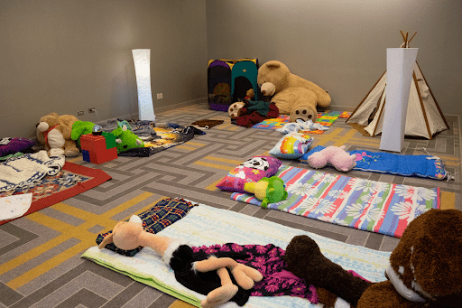 Room with stuffed animals spread across the floor