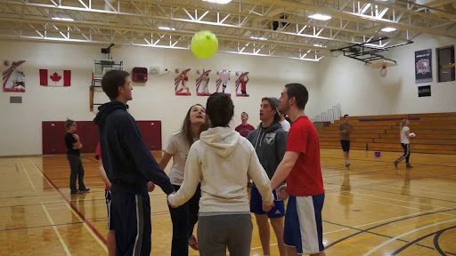 Students holding hands and playing a game with a balloon