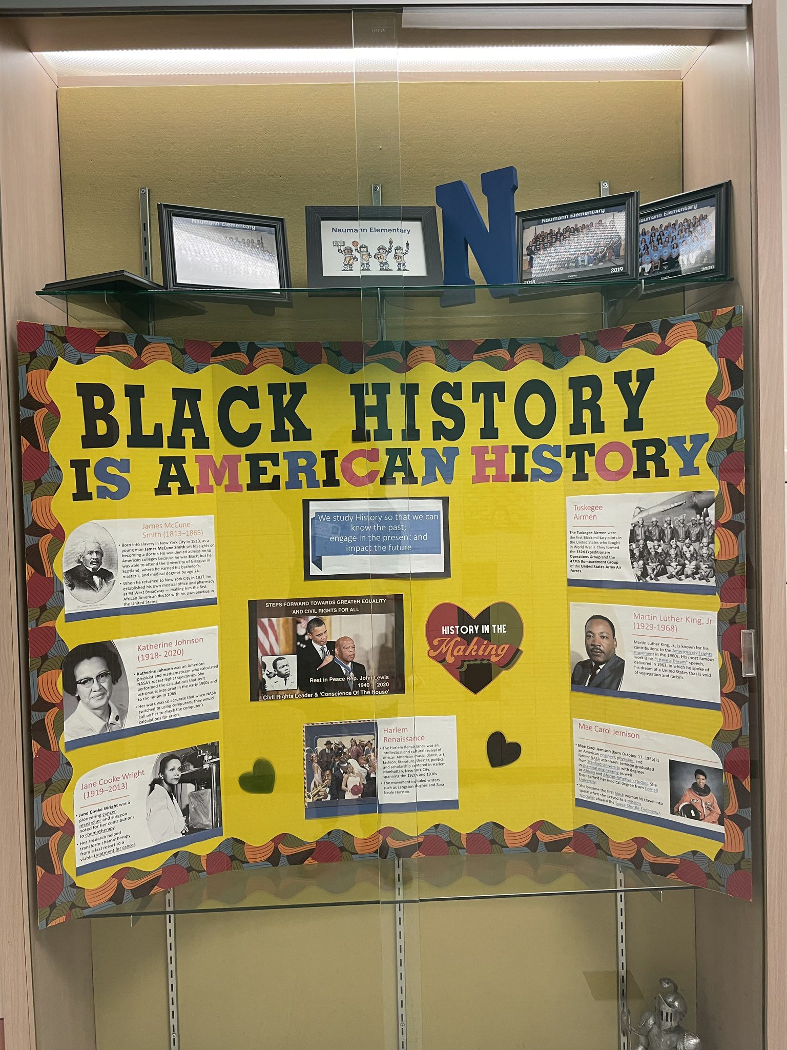 A bright yellow board has writing across it that says Black History is American History. It has photos and descriptions of events and people from Black history. (black history month bulletin board)