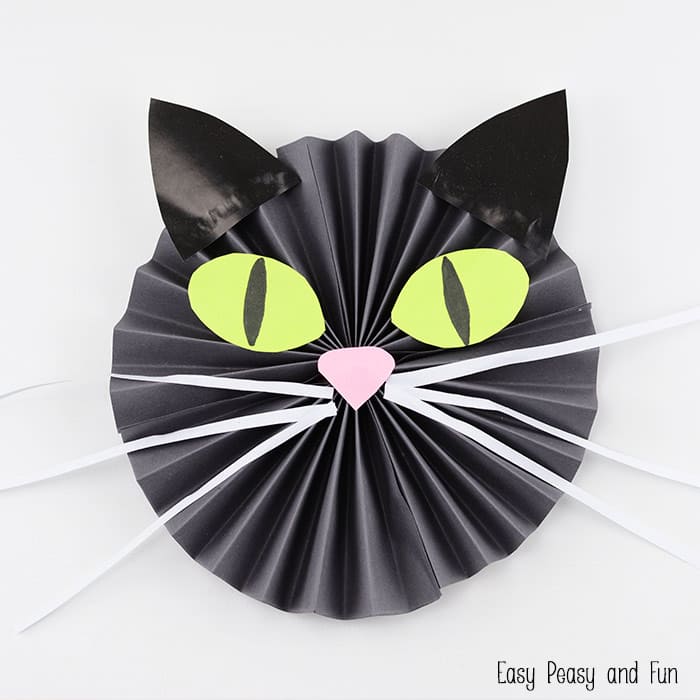 Fall art projects can include black cats. This one is made from black paper folded accordion style to form the face. It also has ears, green eyes, a pink nose, and white whiskers. 