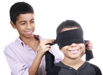 One boy tying a blindfold onto a smiling smaller boy
