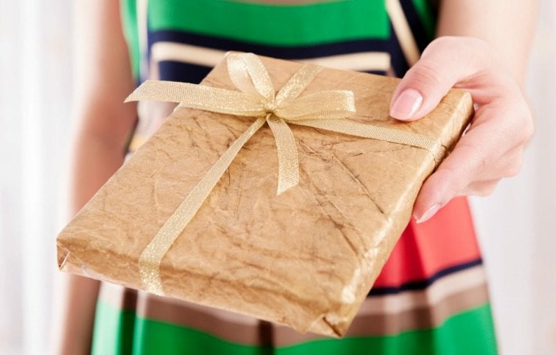 Teacher holding book wrapped in brown paper and gold ribbon