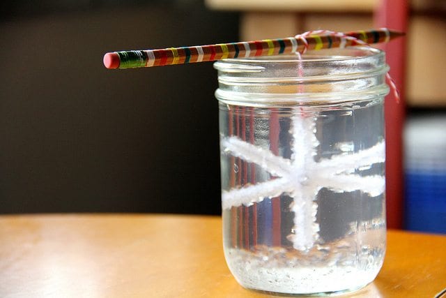 sugar crystal suspended from a pencil over the mouth of a mason jar