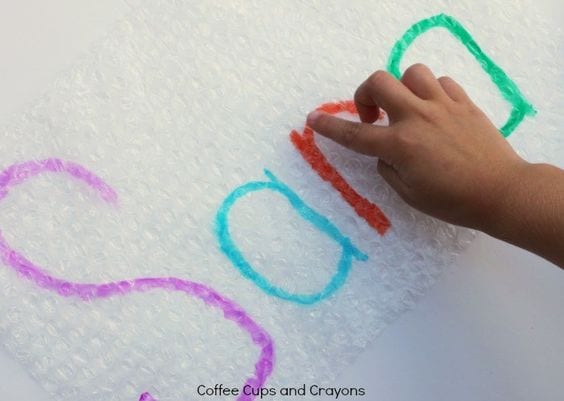 A child tracing the letters of his name written on bubble wrap